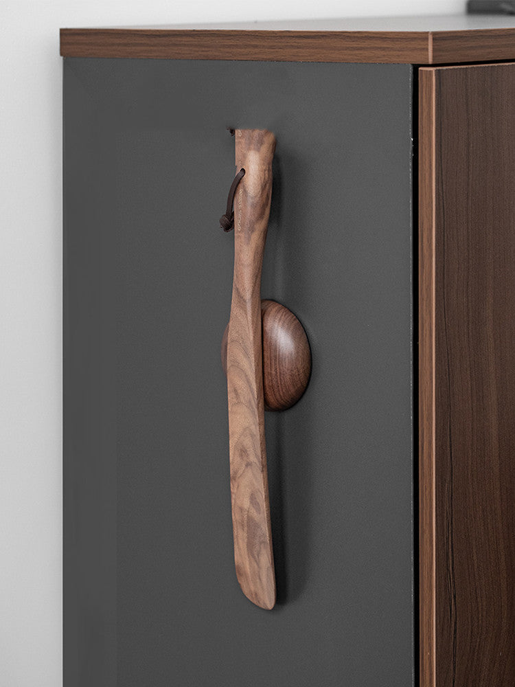 Walnut shoe horn mounted on the side of a cabinet with the magnetic disc