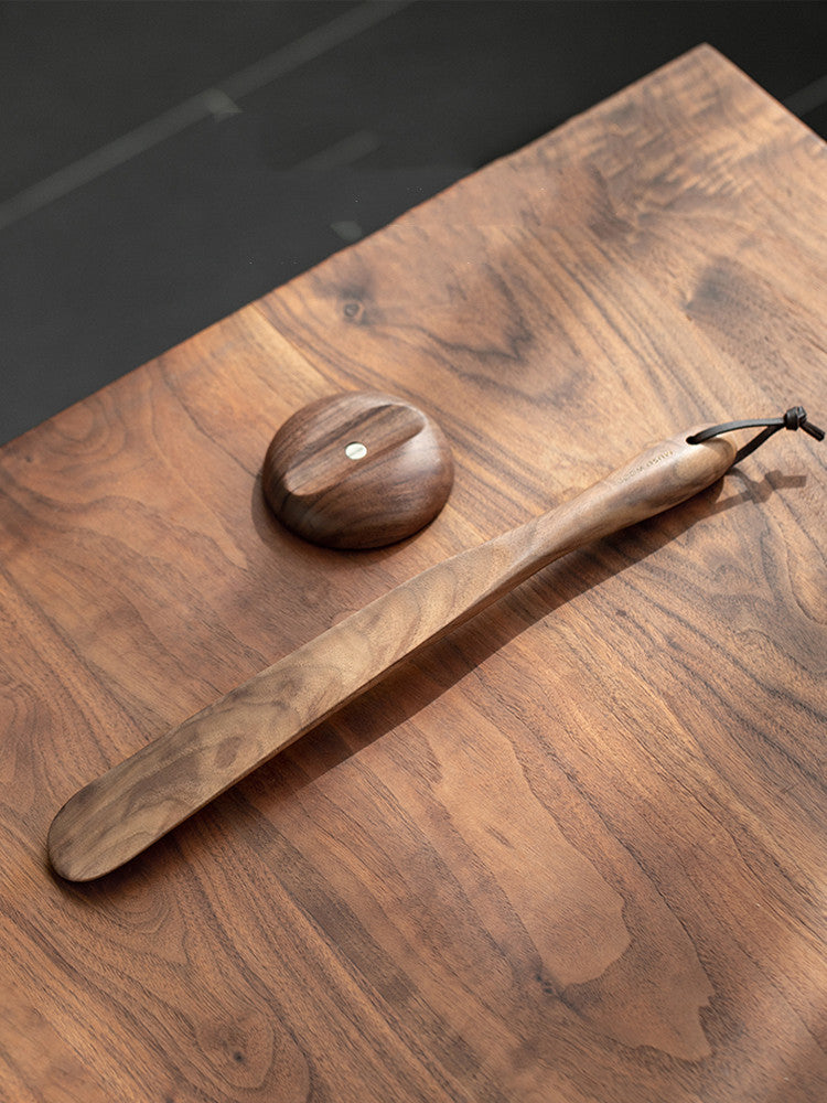 Black walnut shoe horn and its magnetic wall disc on a walnut tabletop